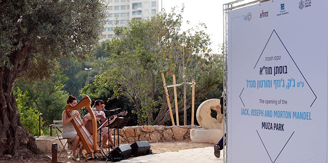 A woman playing the harp and a woman playing the guitar under the trees